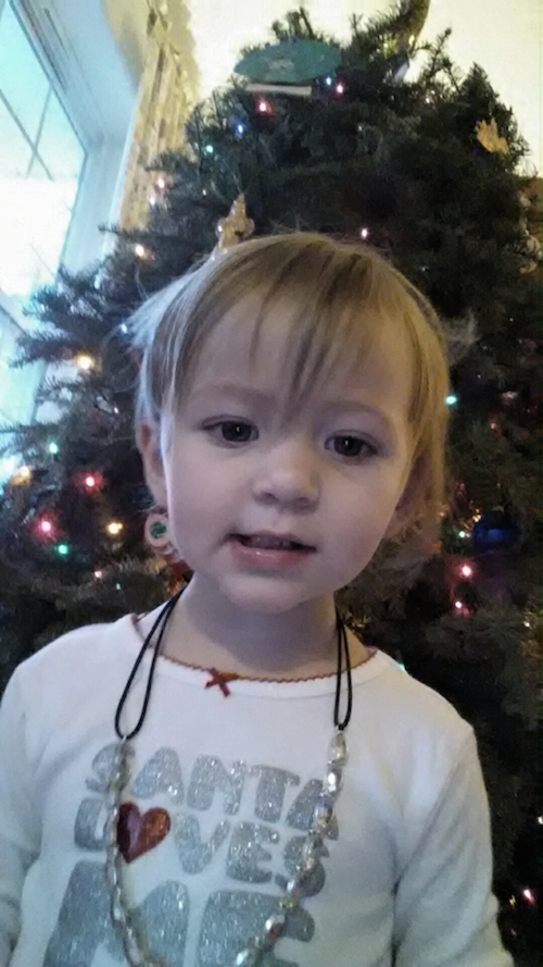 Elise showing off her new necklace in front of the tree