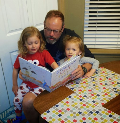 Grandpa reading ‘Dragons Love Tacos’ (their favorite book) to the girls