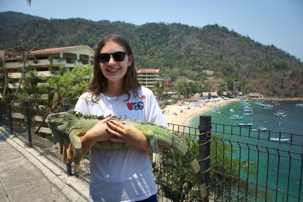 Ava Pellegrini holding Luca the Iguana above Mismaloya beach